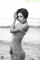 A woman in a wet dress standing on the beach.