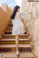 A woman in a white dress is walking up some stairs.