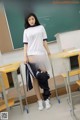 A young woman standing in front of a blackboard in a classroom.