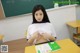 A young woman sitting at a desk in front of a blackboard.