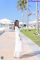 A woman in a white dress standing on a sidewalk.