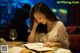 A woman sitting at a table with a glass of wine.