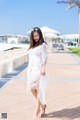 A woman in a white dress is walking on a sidewalk.