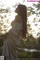 A woman in a white dress standing in the woods.