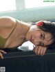 A woman in a green bikini laying on a ledge.