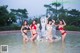 A group of women in bikinis standing in a pool.