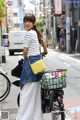 A woman standing next to a bike with a basket on the back.