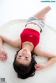 A woman in a red bathing suit laying on a white rug.