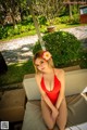 A woman in a red bathing suit sitting on a lounge chair.