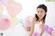 A young woman in a pink dress is surrounded by balloons.