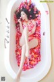 A woman laying in a bathtub covered in rose petals.