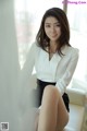 a woman sitting on top of a white couch next to a window