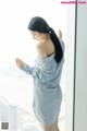 A woman standing in front of a window looking out at the city.