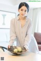 A woman holding a bowl of fruit on a table.