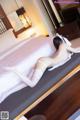 A woman laying on top of a bed in white stockings.