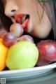 A close up of a woman eating a bowl of fruit.