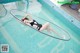 A woman in a black bathing suit laying on a surfboard in a pool.