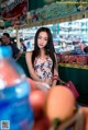 A woman standing in front of a fruit stand.