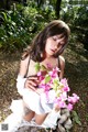 A woman in a white dress holding a bunch of flowers.