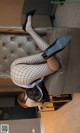 A woman in fishnet stockings and high heels is sitting on a couch.