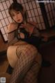 A woman in fishnet stockings is posing for the camera.