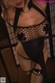 A woman in a black fishnet lingerie posing for the camera.