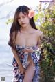 A woman in a floral dress posing by the water.