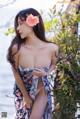 A woman in a floral dress posing by the water.