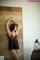 A woman leaning against a wooden wall in a black lingerie.