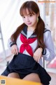 A woman in a school uniform sitting on a chair.