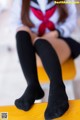 A woman in a school uniform sitting on a yellow chair.