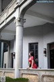 A woman in a red dress standing on a balcony.