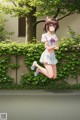 A girl in a white shirt and skirt is jumping in the air.