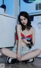 A woman sitting on the floor in front of a washing machine.