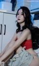 A woman sitting on top of a washing machine in a kitchen.