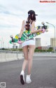 A woman walking down a street holding a skateboard.