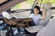 A woman sitting in the driver's seat of a car with her feet up.