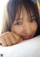 A young woman laying on top of a bed smiling.